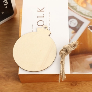 Unfinished wooden Christmas ball ornament with twine string on a cozy desk setting