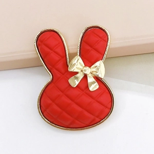 Detailed macro view of a red cartoon rabbit charm with gold bow and lattice texture