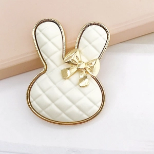 Detailed macro view of a white rabbit-shaped accessory with gold trim and plaid pattern