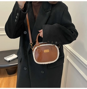 Brown leather handbag featuring plush white fleece trim and a golden metallic logo detail