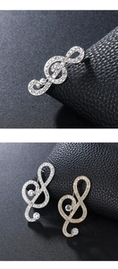 Detailed close-up of treble clef music note brooch with shimmering white rhinestones