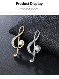 Macro detail of music note brooches with sparkling crystals and pearls on black leather