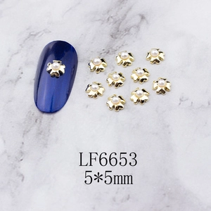 Detailed macro view of 5x5mm gold metal nail art charms with pearls and scalloped edges