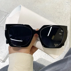 Detail of black square oversized sunglasses with a white faux leather foldable case