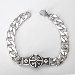 Macro detail of stainless steel cuban link bracelet featuring skull and cross embossing