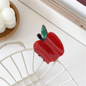 Sparkly red apple hair claw clip in acrylic with green leaf on a white grid background