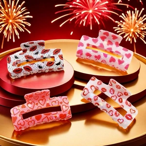 Set of four rectangular heart and lip print hair claws on a festive red holiday display