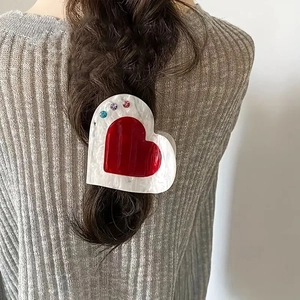 White marble heart hair claw clip with red gemstone decoration on braided hair