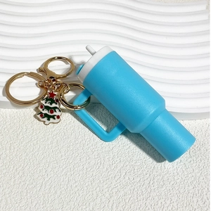 Macro shot of blue mini tumbler keychain with golden ring and small Christmas tree charm