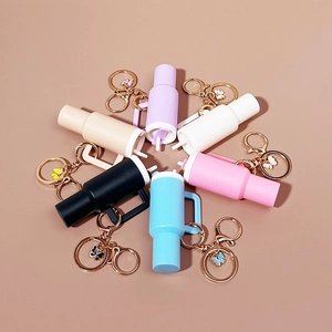 Mini tumbler cup keychains in seven pastel colors arranged in a circle on plain background
