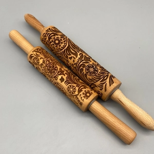 Close-up of laser-engraved wooden rolling pins with floral and snowflake patterns