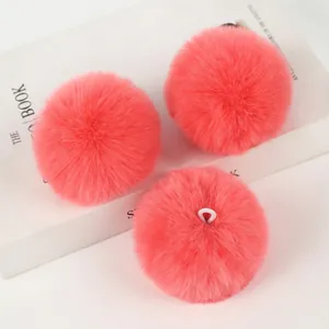 Three coral pink faux rabbit fur pom poms with lanyards for bags and keychains