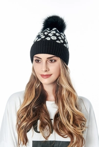 Detail of a black and white polka dot winter knit beanie with a fluffy faux fur pompom
