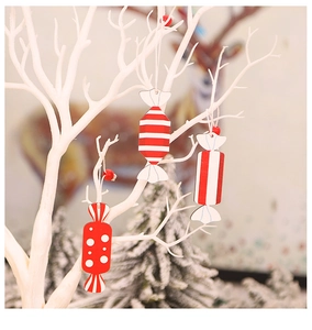 Close-up of red and white striped wooden candy ornaments hanging on a Christmas tree