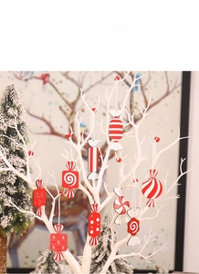 Close-up of red and white wooden candy ornaments hanging on a white Christmas tree