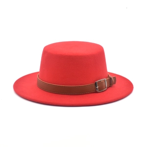 Detail of red wool felt boater hat with a brown leather strap and silver buckle