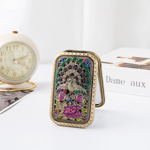 Detailed view of vintage bronze folding mirror with peacock and peony enamel relief decoration