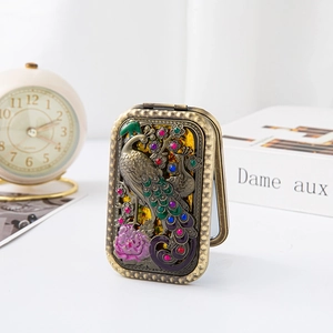 Detail of vintage bronze pocket mirror featuring embossed peacock and floral design
