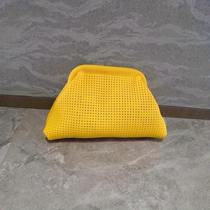 Macro detail of bright yellow knitted cloud clutch bag showing soft woven texture