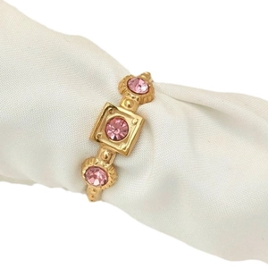 Vintage gold geometric ring featuring three pink faceted stones on a white silk background