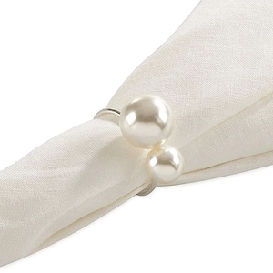 Silver metal napkin ring with white pearls on a white linen napkin for wedding decor