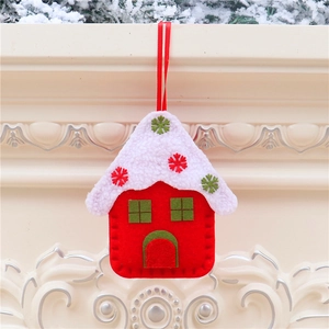 Detail of red and green felt house ornament hanging on a snowy mantel for Christmas