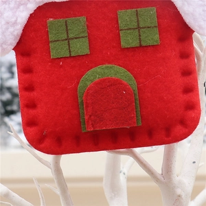 Close-up of a red felt house Christmas ornament with white plush trim and green accents