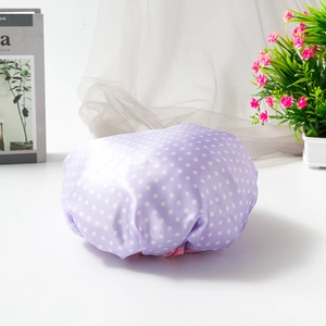 Detail of waterproof purple shower cap with white polka dots and elastic band