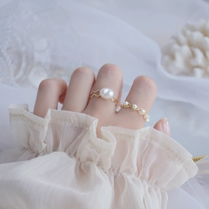 Detail of 14k gold-plated rings with natural freshwater pearls on white lace fabric