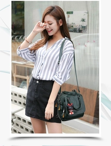 Street style view of deep green textured leather convertible handbag with a cute charm