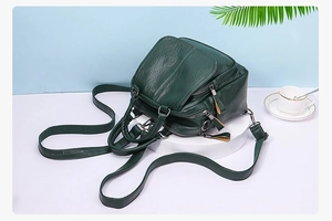 Detail view of dark green multi-functional PU leather backpack with layered zippers