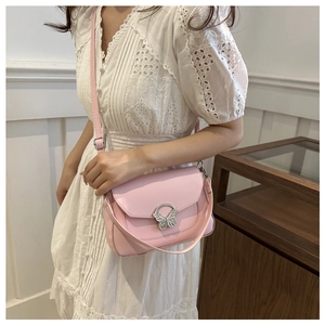 Detail of pink faux leather bag featuring a silver butterfly-shaped metal buckle and strap