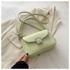 Elegant mint green leather crossbody bag with metallic butterfly clasp on blazer