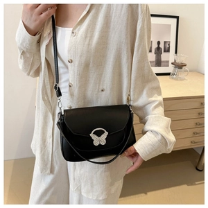 Detail of elegant black crossbody bag featuring a silver butterfly clasp and matte leather