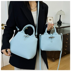 Detail of light blue lychee pattern leather bucket bag with metallic bamboo toggle closure