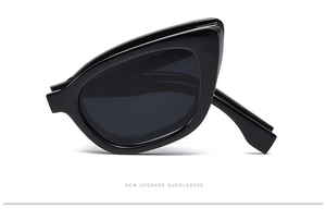 Detail view of foldable black cat-eye sunglasses with thick frames and dark grey lenses