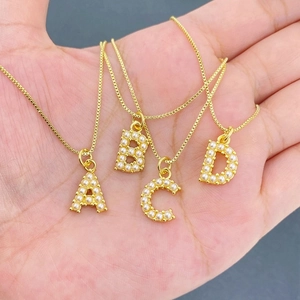 Gold box chain necklaces with faux pearl inlaid A-D letter pendants held in hand