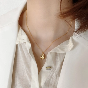 Close-up of a minimalist gold irregular wrinkled pendant necklace worn by a model