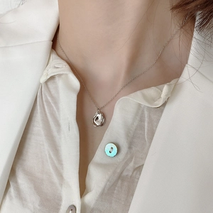 Detail of silver liquid metal irregular pendant necklace worn on a silk shirt
