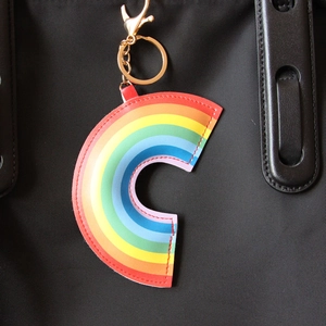 Detail of a vibrant rainbow C-shaped PU leather keychain charm with golden metal hook