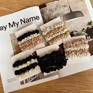 Silk satin scrunchie set in assorted colors displayed on a magazine and wooden table