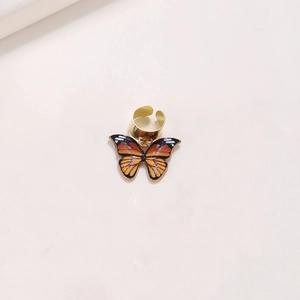 Close-up of golden metal hair ring with a detailed orange and black butterfly pendant