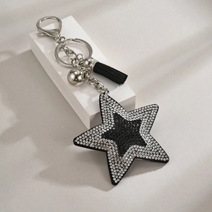 Detail of a black sequin star keychain with sparkling rhinestones and a black fringe tassel