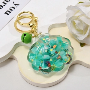 Close-up of a sea shell liquid keychain with green bell and colorful beads detail