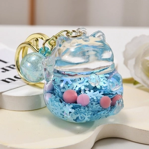 Macro shot of liquid glitter lucky cat keychain with blue fluid and pink pearls inside