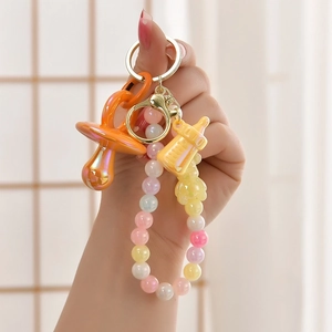 Detail of colorful DIY keychain with orange pacifier, yellow bear and bead chain