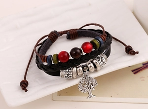Close-up of woven leather bracelet featuring a silver Tree of Life charm and vintage beads