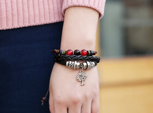 Close-up of woven leather bracelet featuring wooden beads and a Tree of Life pendant