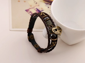 Detail of multilayer leather bracelet featuring bronze anchor charms and heart pendant