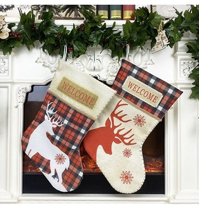 Détail de chaussettes de Noël à carreaux rouges et blancs suspendues à une cheminée